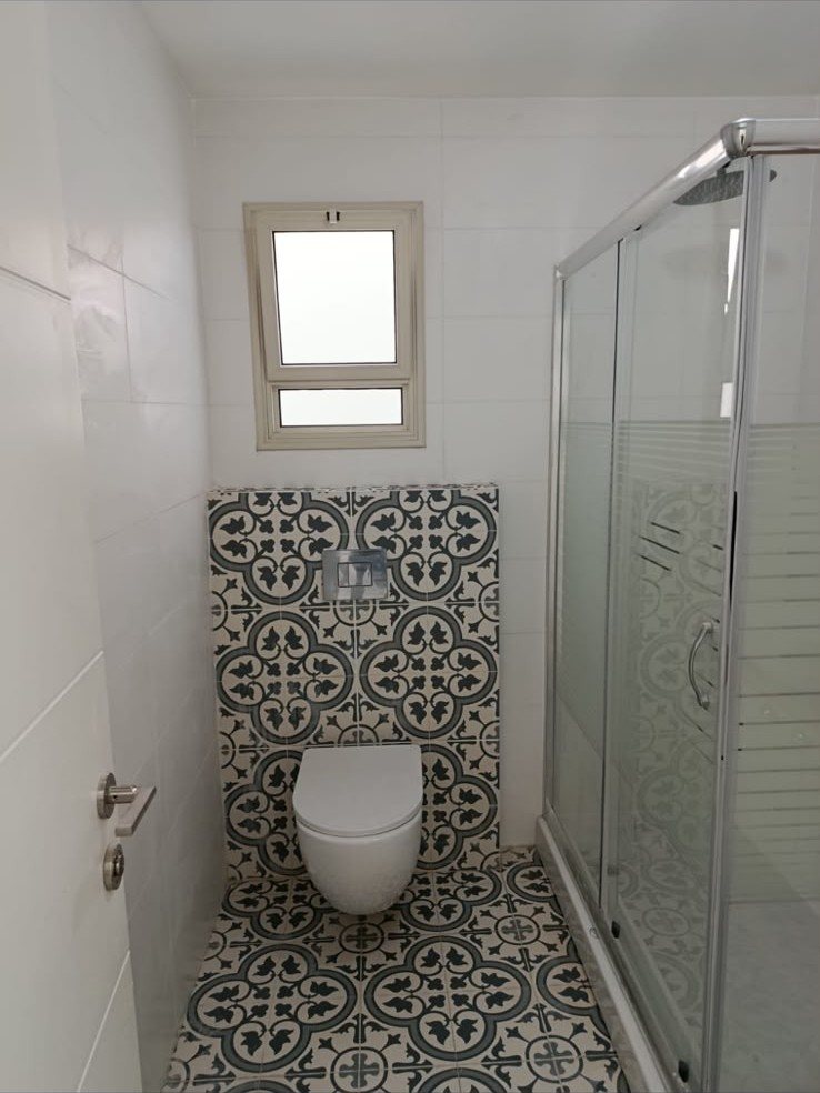 שירותים במבנה יביל — אסלה תלויה, חיפוי קיר מעוטר ומקלחון